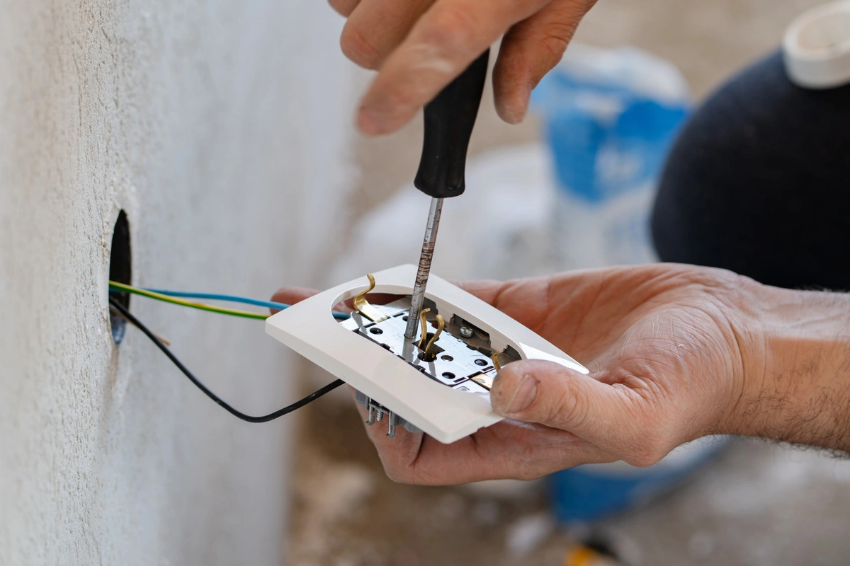 Technicien installant une prise électrique murale.