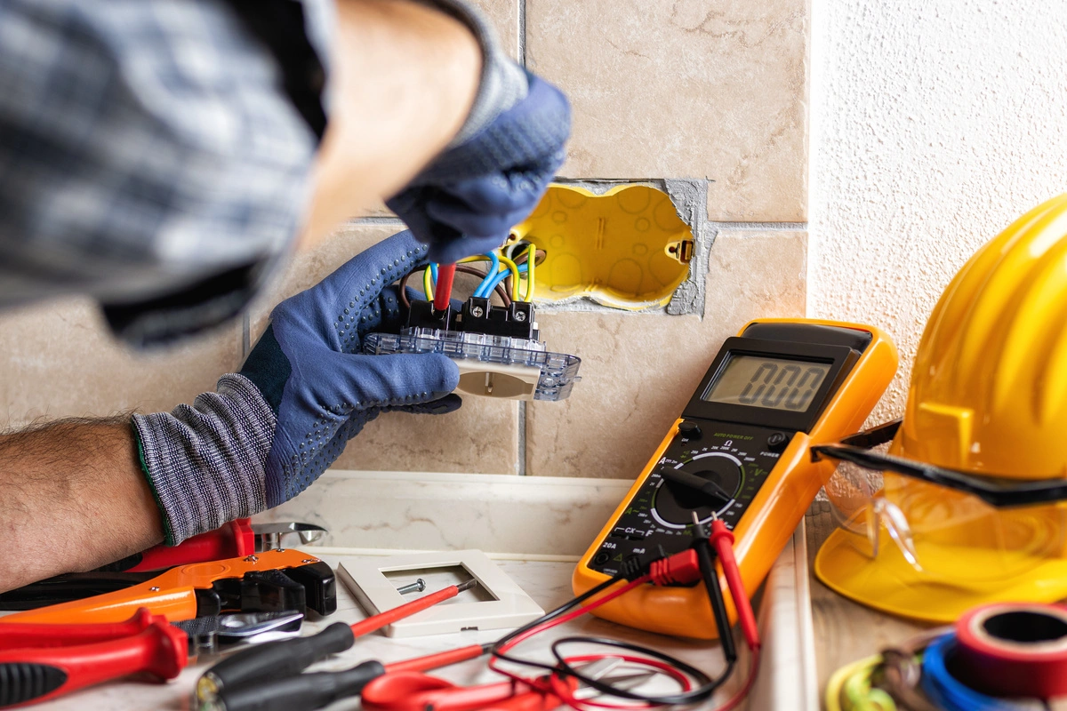 Travaux d'électricité générale avec un technicien vérifiant les connexions électriques.