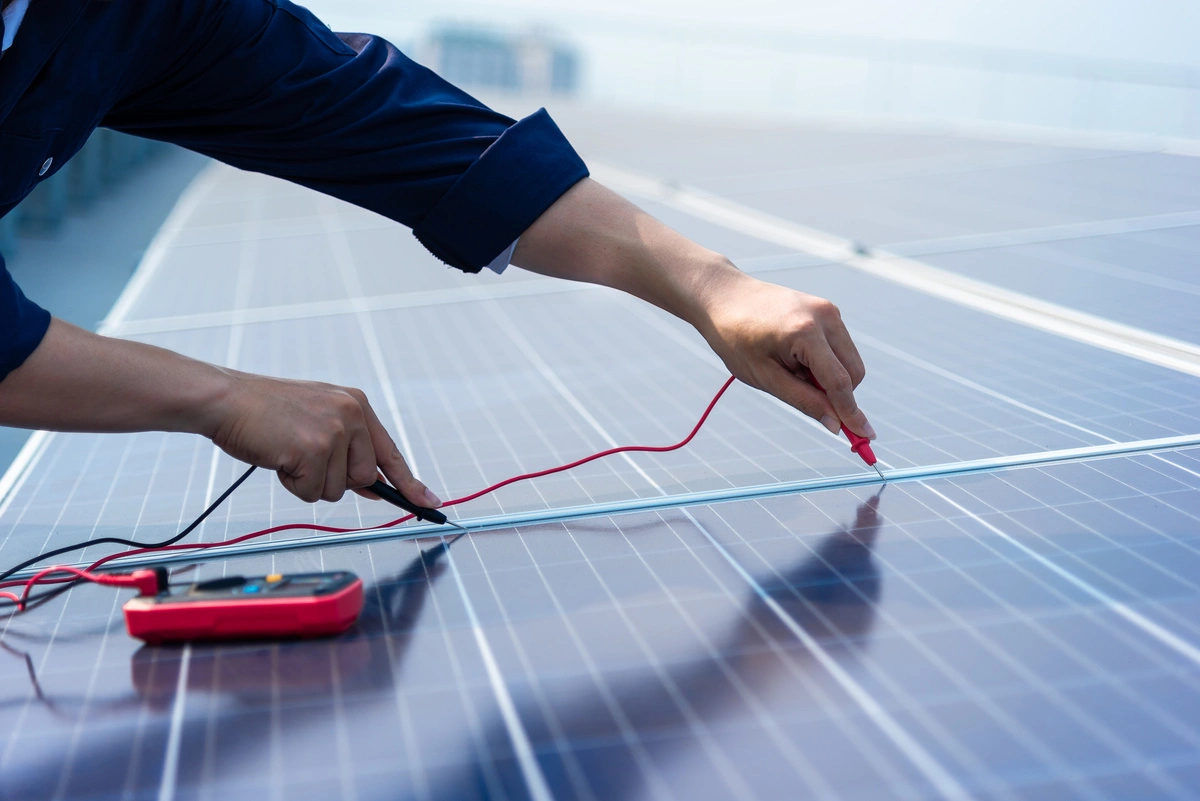 Technicien effectuant des tests sur des panneaux photovoltaïques installés sur un toit.