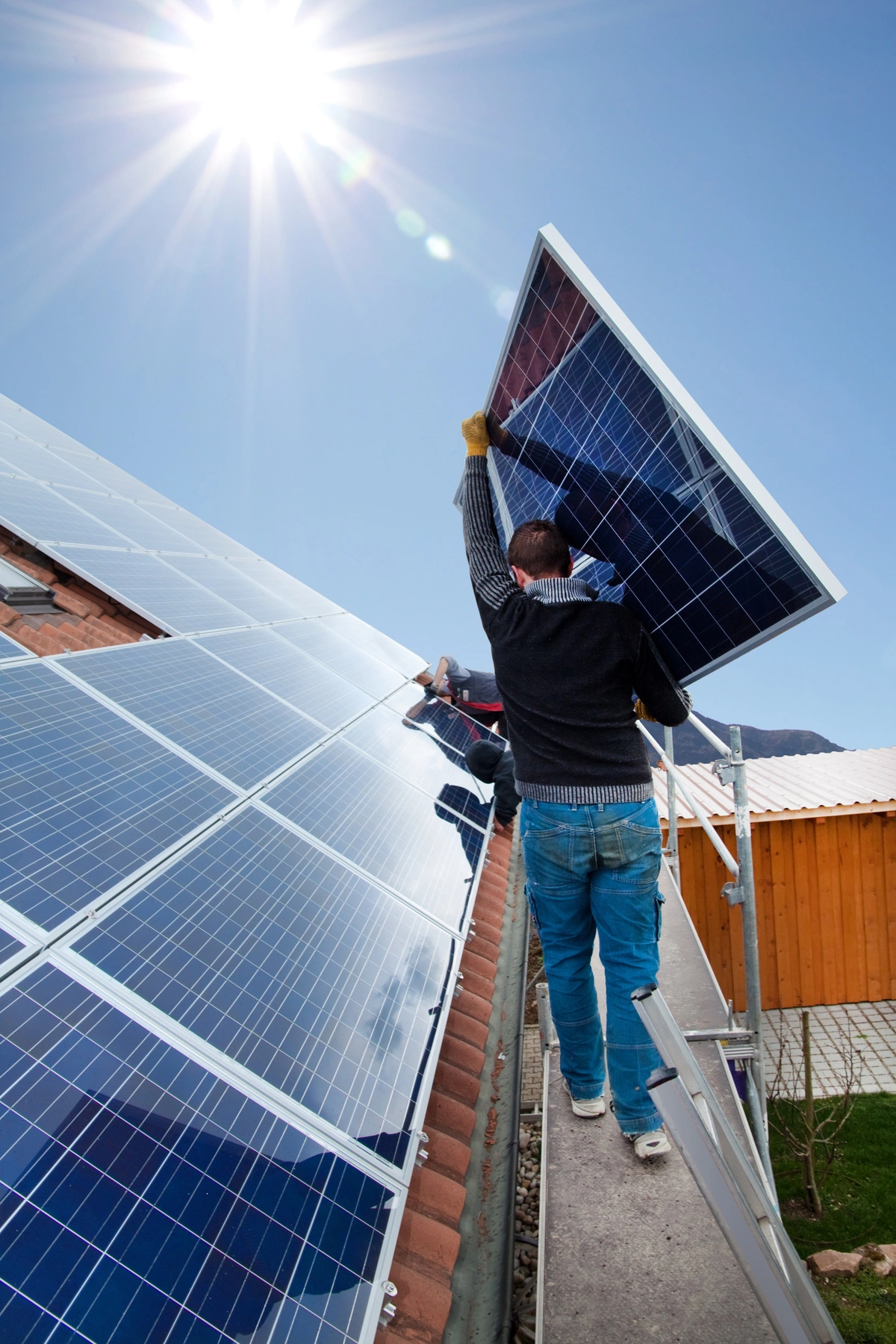 Installation de panneaux photovoltaïques sur un toit en pente par un technicien.