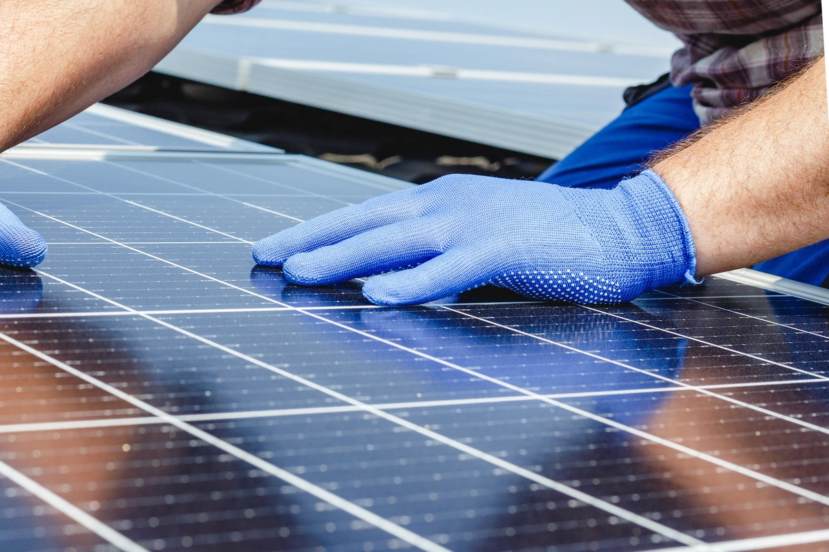 Pose de panneaux photovoltaïques par un technicien portant des gants bleus
