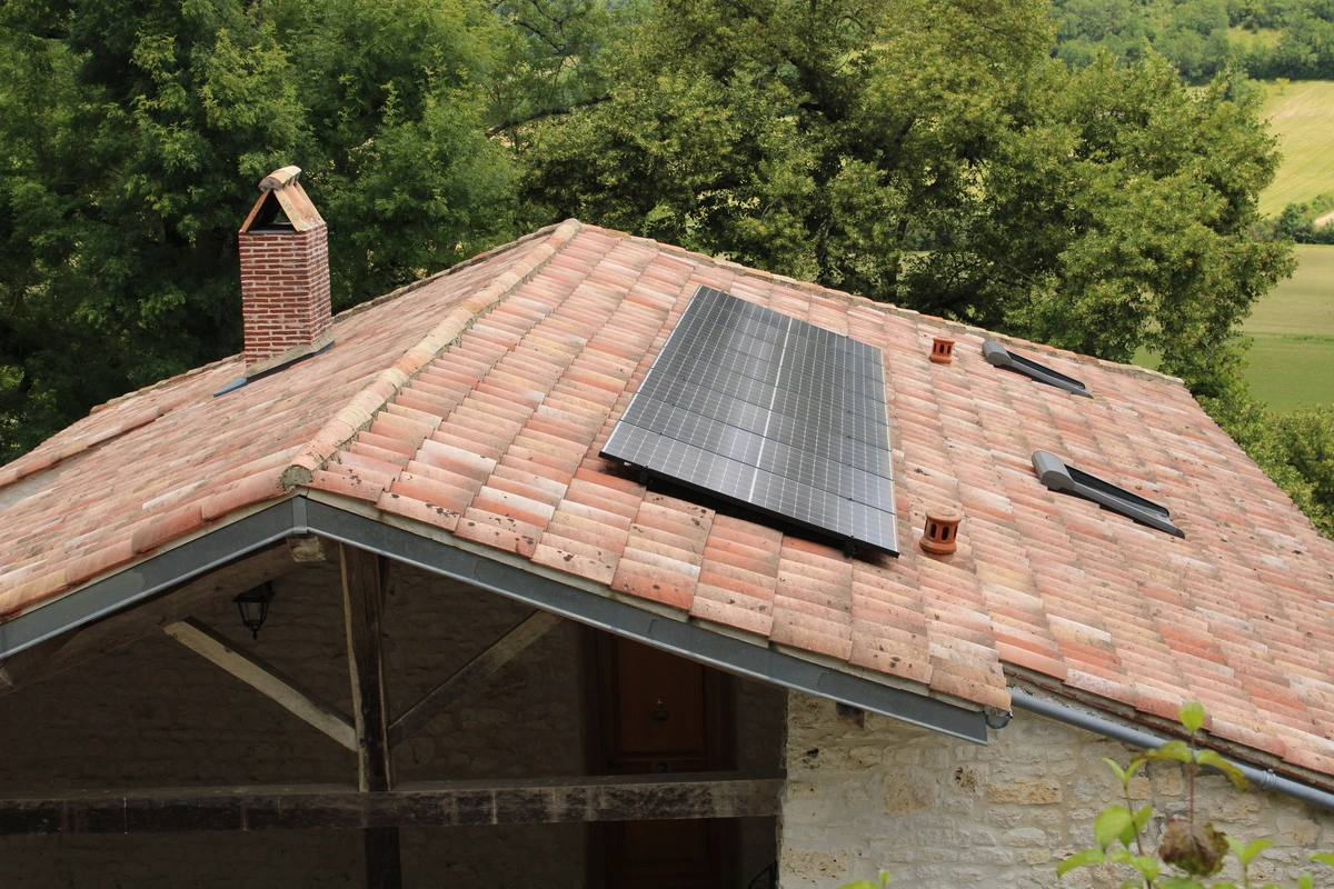 Panneaux photovoltaïques installés sur le toit en tuiles d'une maison en campagne.