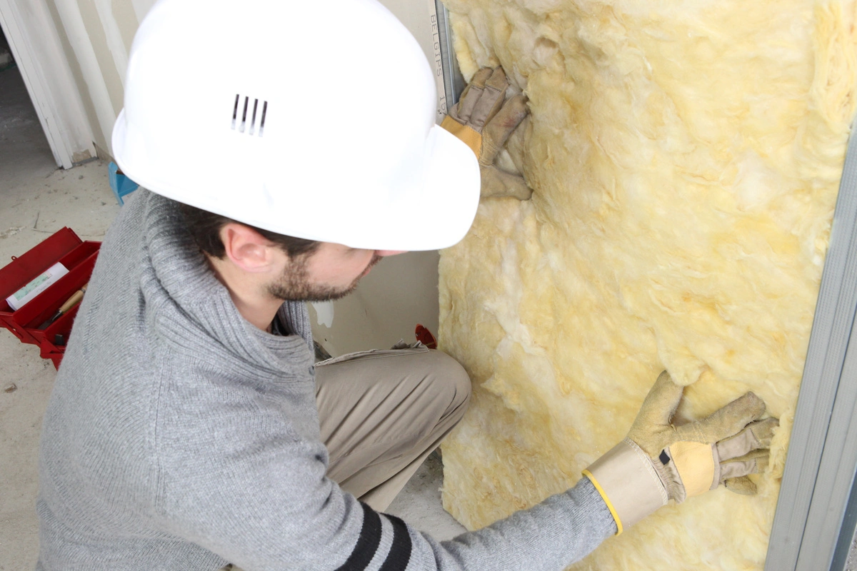 Technicien installant de l'isolation sur un mur intérieur.